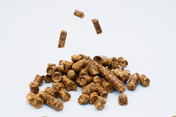 Falling individual pellets on a slide of pellets on a light background. Wood sawdust pressed into...