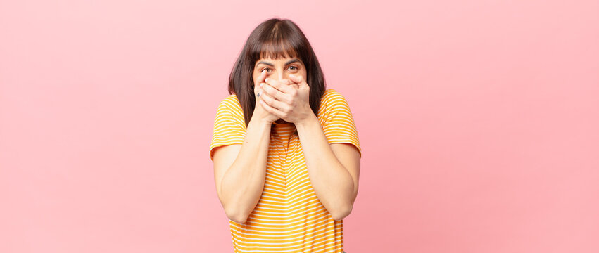 pretty woman covering mouth with hands with a shocked, surprised expression, keeping a secret or saying oops