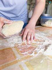 Left hand spreads flour on table. In right dough