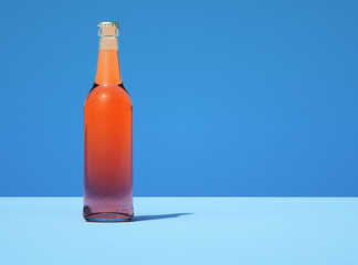 Transparent glass beer bottle on retro light blue color background. Bottle filled with yellow liquid.