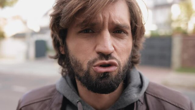 Portrait of Caucasian Bearded Man Emotional Talking to the Camera Outdoors. Recording Video Blog standing on the Street having Attractive Appearance and Style Haircut. Social Media. People. Devices.