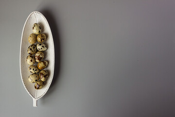 Quail eggs on a leaf-shaped plate, minimalism. elegant easter background, place for text, copy space