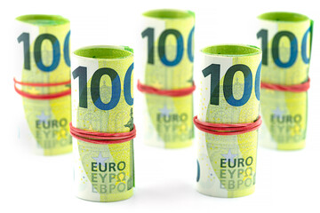 Macro shot of the European Union 100 EURO banknote, a few bills rolled up in a rubber band, isolated on a white background.