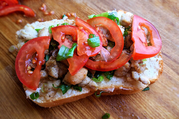 Sandwich with chicken tomatoes and herbs on wood background, close-up blurred background