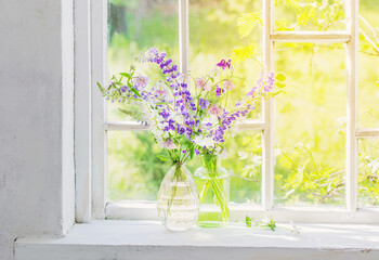 summer flowers in vase on windowsill in sunlight