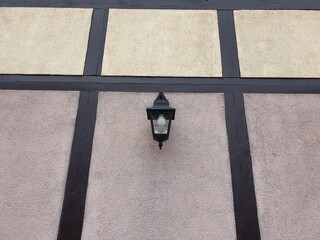 Lonely lantern on the facade of the building. The house was built in the old style and painted gray.