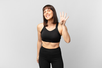 athlete woman smiling and looking friendly, showing number four or fourth with hand forward,...
