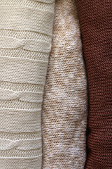 Stack of folded sweaters in neutral colors. Top view.