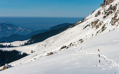 Fototapeta na wymiar Snowy hiking trail in Bucegi mountain range down to the valley - Romania