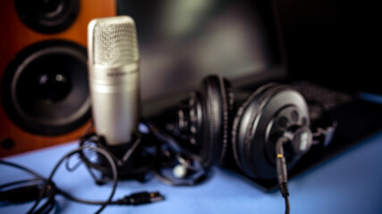 Blured background. Studio microphone, headphones, speakers and computer. Home studio recording for sound mixing, sound design and music production.