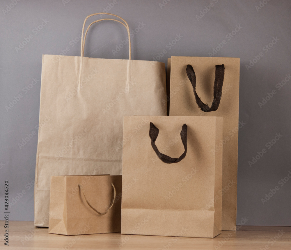 Wall mural Set blank brown paper carrier bags with handles for shopping on wood table