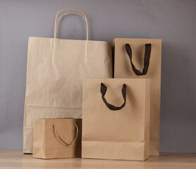 Set blank brown paper carrier bags with handles for shopping on wood table