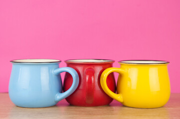 Three colorful cups at wood table background