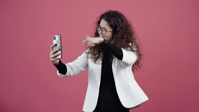 Beautiful teen with curly hair, talking to friends on the phone with the help of the front camera.