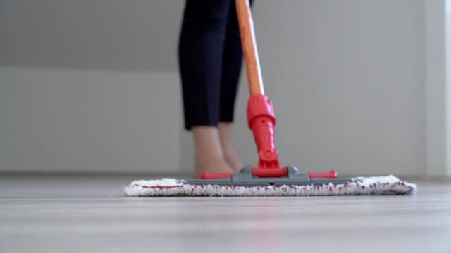 Barefoot woman cleaning floor with wet mop pad