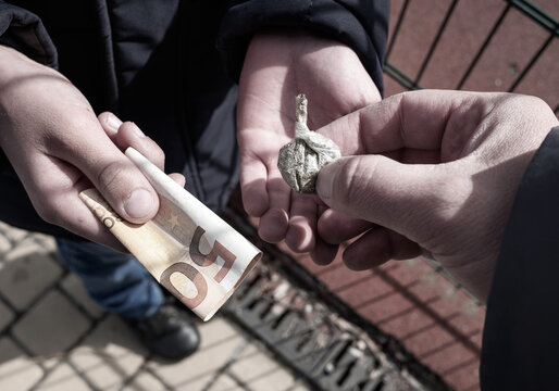 Symbolic Image Of The Social Problem Of School Drug Addiction To Illustrate Crime News Stories. Drug Courier Sells Drugs To A Schoolboy. Toned, Close-up.