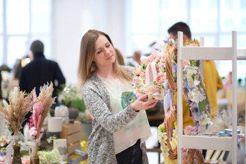 business owner selling behind counter with her bouquet of dried flowers at local market of...