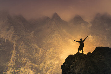 silhouette of a person on a mountain with arms up to the sky 