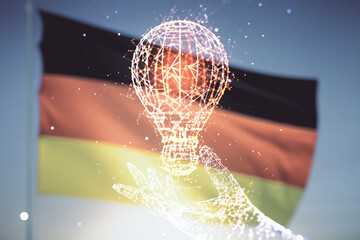 Abstract virtual light bulb hologram on flag of Germany and blue sky background, idea concept. Multiexposure