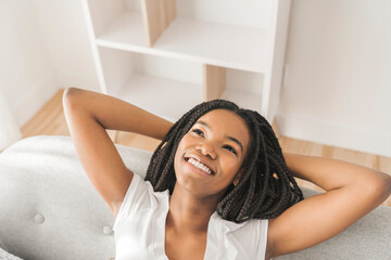 Naklejka premium Young African American teen on a sofa in her living room relaxing