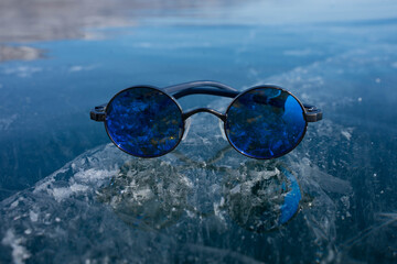 blue glasses lie on transparent ice