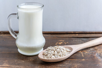 a mug of milk and a spoon of oatmeal on an old wooden table