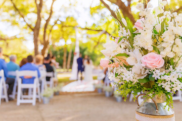 Fototapeta na wymiar Outdoor wedding with flowers in focus and wedding guests and bride and groom out of focus