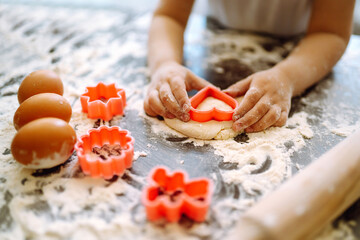 A little chef cutting out shapes heart and making ginger cookies. Close up of boy hands carving dough. Easter baking preparation. Children's art project, a craft for children.