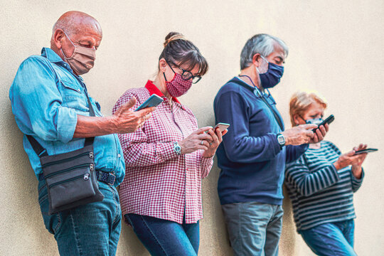 Senior people using smartphones with face mask on - Old man in focus