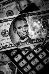 Five dollar bill with a magnifying glass and calculator