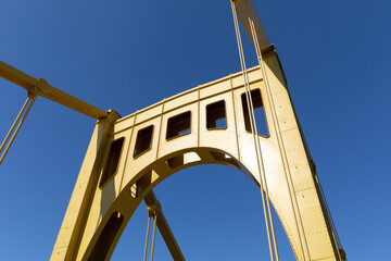 Fototapeta premium Upright of a self anchored suspension bridge painted bright yellow against a deep blue sky, horizontal aspect