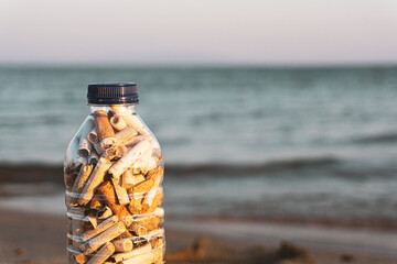 A bottle full of cigarette. Environmental pollution conceptual photo. Allegorical closeup that drawing attention to water and bad environment pollution reasons, no smoking addiction. 