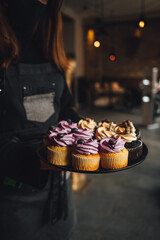 Waiter is serving a platter of yummy blueberry and chocolate cupcakes