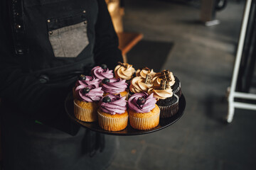 Waiter is serving a platter of yummy blueberry and chocolate cupcakes
