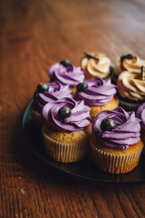 A platter with yummy blueberry and chocolate cupcakes on the wooden surface; background with a copy space