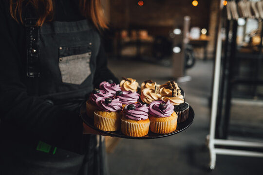 Waiter is serving a platter of yummy blueberry and chocolate cupcakes