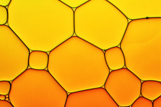 Bright Hot Background Closeup of Oil Drops in Water. Abstract Art Macro Photo of Liquid Surface with Gradient Yellow and Orange Bubbles.