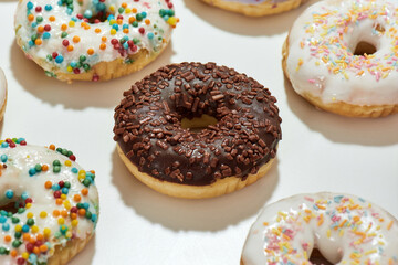 Close up of delicious chocolate round glazed donut with colorful sprinkles