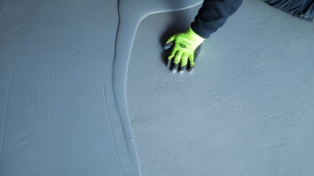 Worker, coating floor with self-leveling epoxy resin in the workshop of the plant