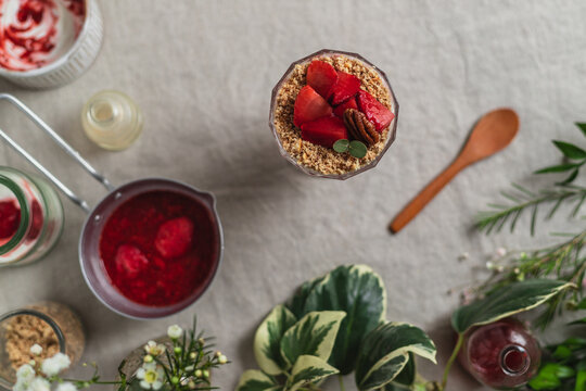 Top view composition of glass of delicious fresh berry drink garnished with cut strawberries and nuts served on table