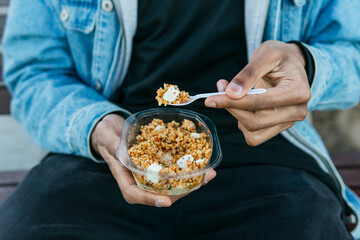 Crop anonymous ethnic male with appetizing healthy food with soft cheese cubes in plastic container to go