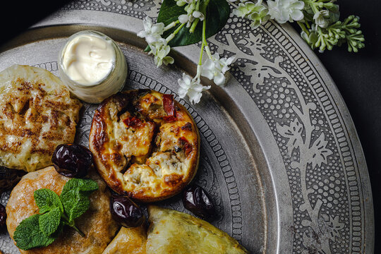 High angle of assorted tasty Arabic food with salsa and fresh mint leaves near almonds during Ramadan holidays