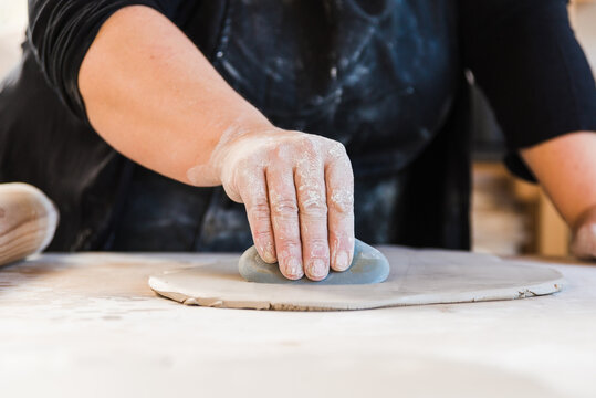 Crop unrecognizable artist cutting out circles from clay while working in workshop