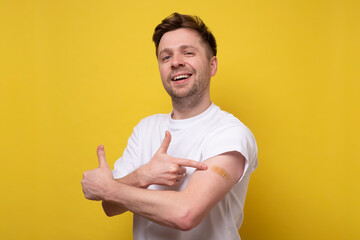 Caucasian man showing his vaccinated arm. He received a corona vaccine looking at camera.