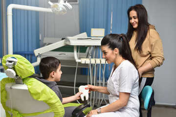 The dentist is talking to the child and the mother is standing nearby