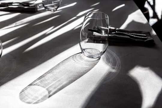 Beautiful shadow of a glass on the table in a restaurant. Quarantine.  Serving table