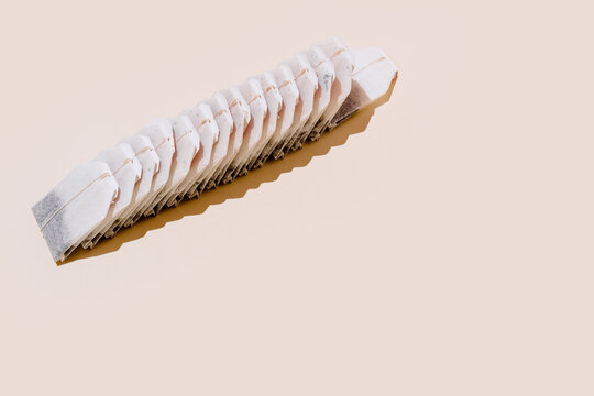 From above of paper tea bags arranged in row on beige background with empty space