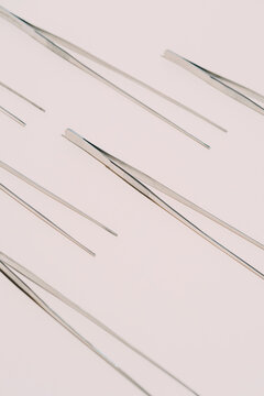 From above of pattern of metal tweezers placed on white background in studio