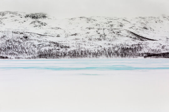 Scenic landscape of frozen lake located against snowy mountains in winter in Norway