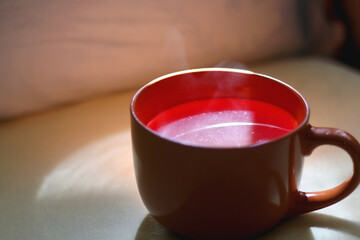 Cup of warm tea on a bed. Selective focus.